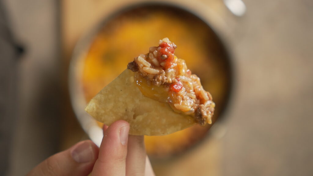 tortilla chip with cheesy taco rice on it
