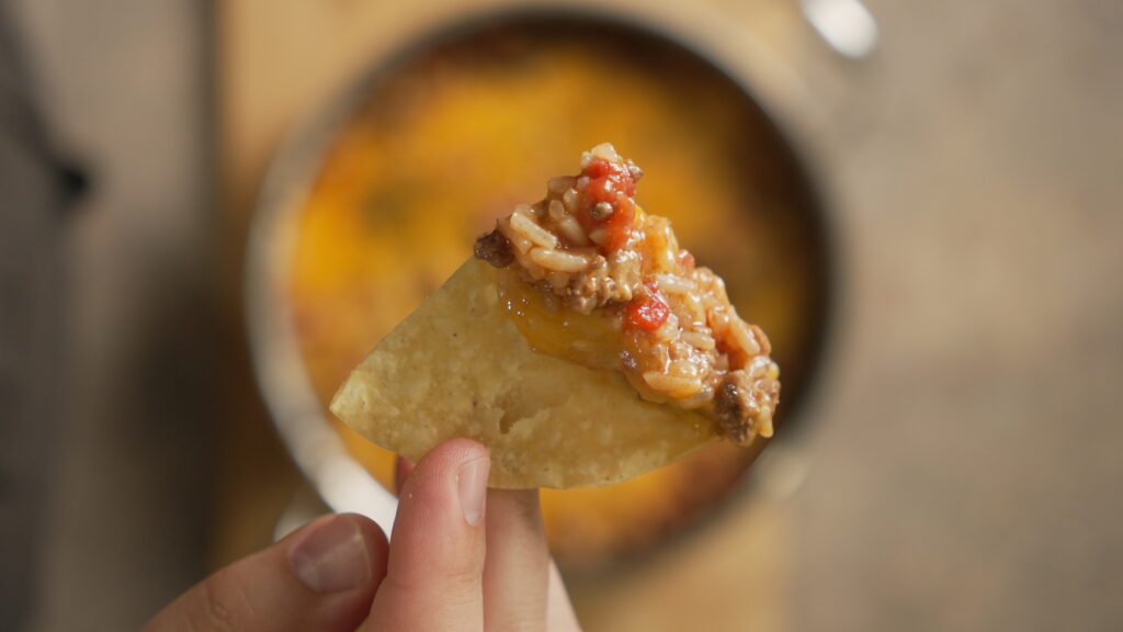 tortilla chip with cheesy taco rice on it
