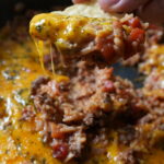 pan of cheesy taco rice with a tortilla chip dipping into it