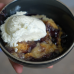 a bowl of blueberry dump cake with vanilla ice cream scoop