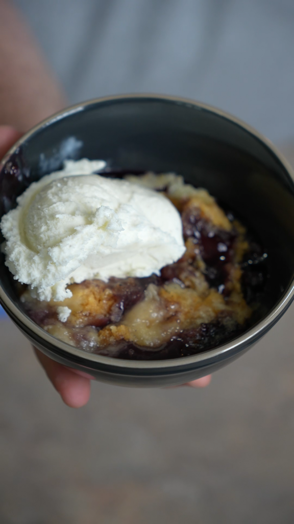 a bowl of blueberry dump cake with vanilla ice cream scoop