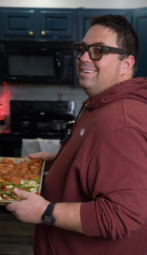 Justin holding a sheet pan of veggies and chicken
