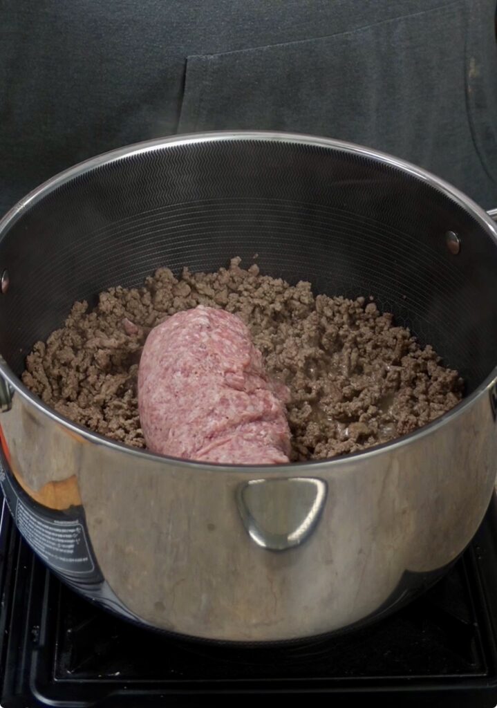 mixing sausage and ground beef in pot