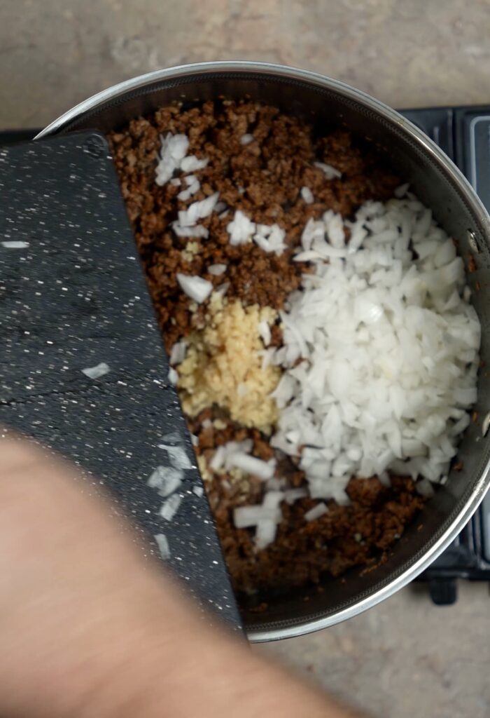adding onions to pot of ground beef