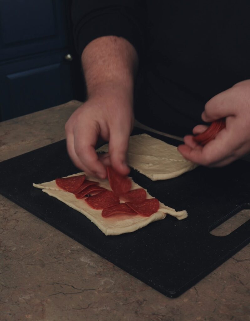 adding pepperoni to dough