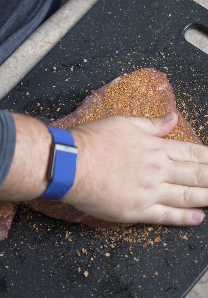 patting seasonings on steak