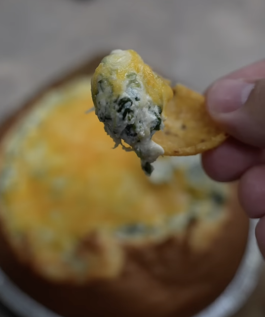 eating spinach dip with a Frito chip