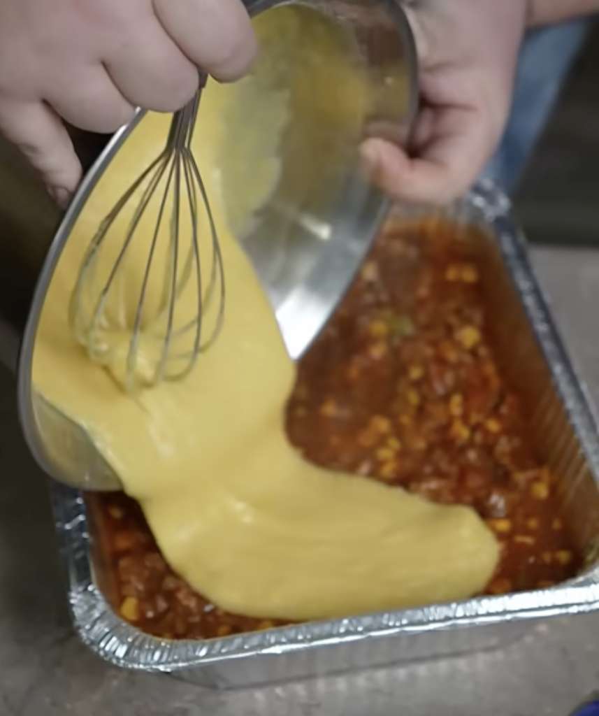 putting cornbread batter over mixture