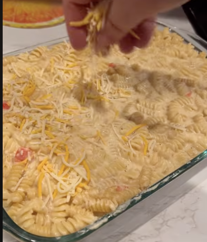 sprinkling cheese on top of pan of Alfredo bake
